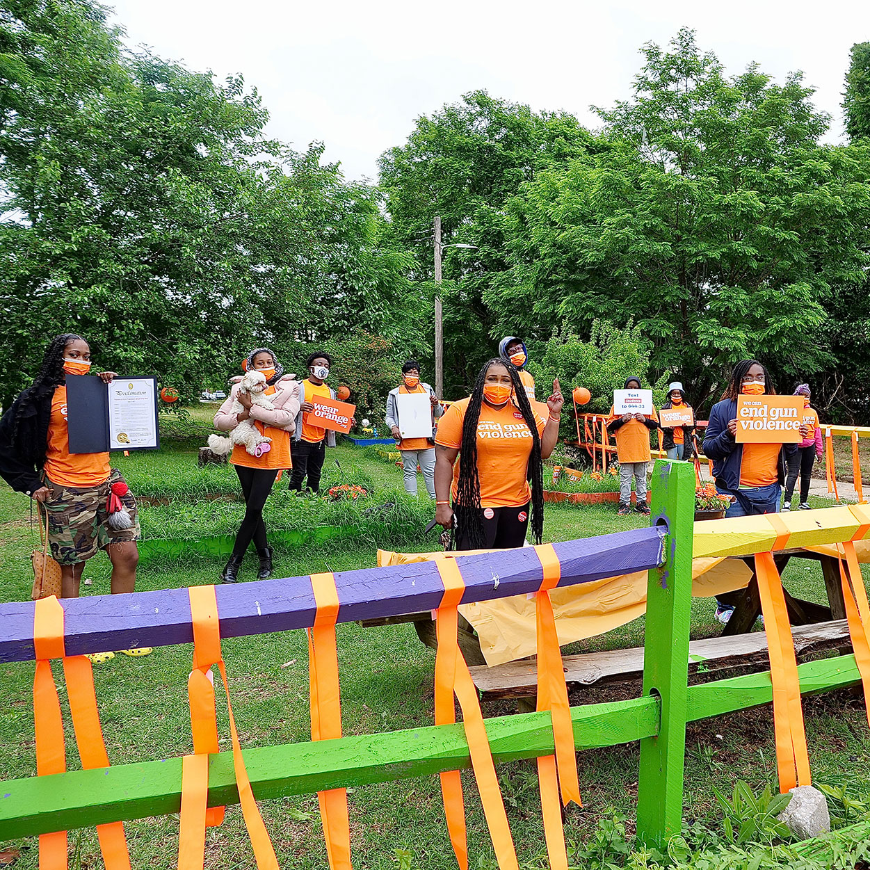 Let's Thrive Baltimore volunteers stand in a garden decorated with orange ribbons