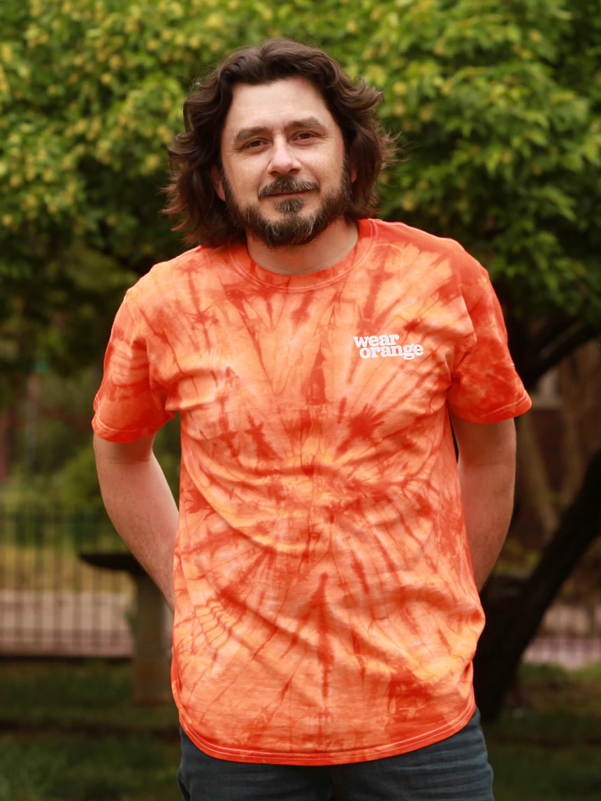 A man wears a tie-dye Wear Orange t-shirt
