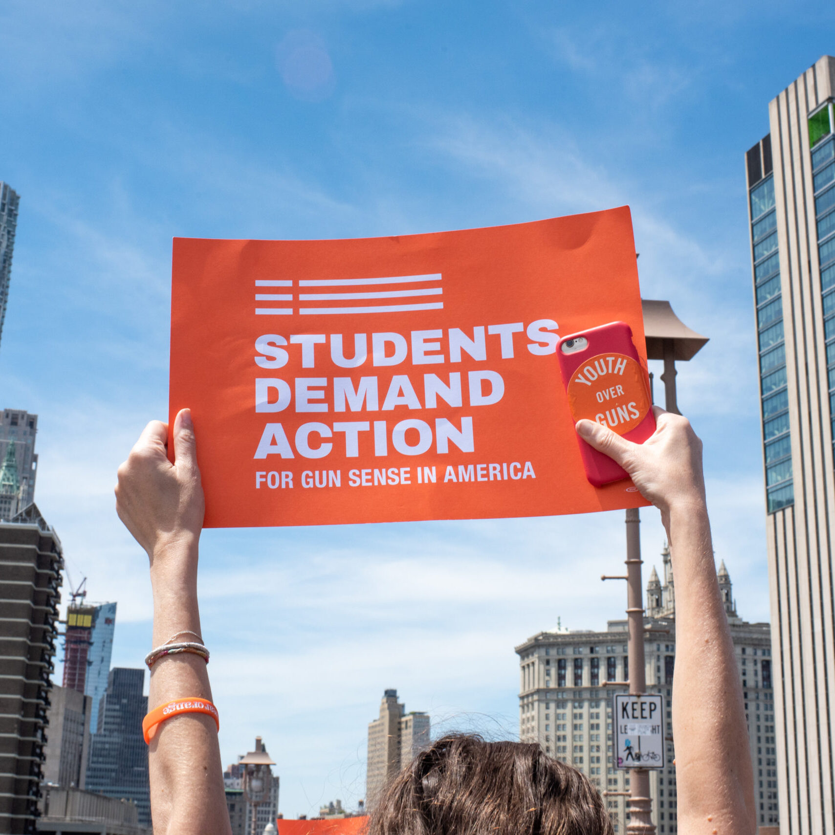 A person holds up an orange Students Demand Action sign